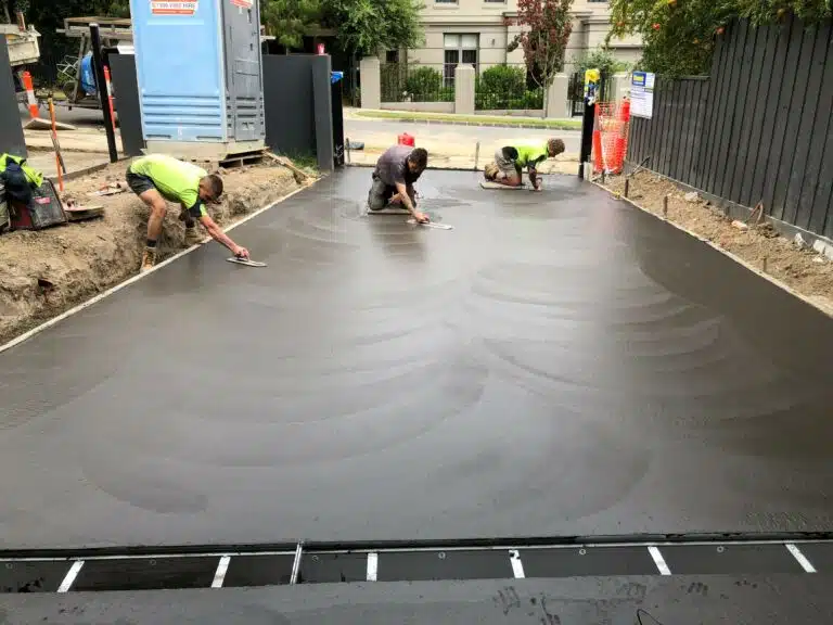 Concrete crew finishing the surface of a freshly poured residential driveway